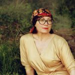 woman in brown long sleeve shirt wearing black and brown floral bandana