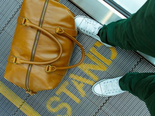 person stranding beside brown leather handbag