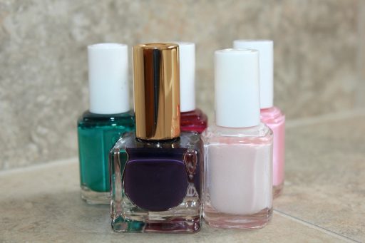 Meerdere flesjes roze nagellak in verschillende tinten naast elkaar op een witte ondergrond