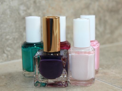 Meerdere flesjes roze nagellak in verschillende tinten naast elkaar op een witte ondergrond