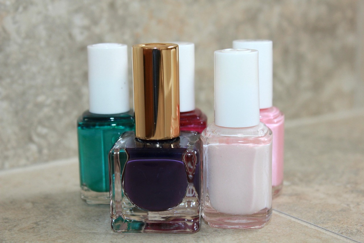 Meerdere flesjes roze nagellak in verschillende tinten naast elkaar op een witte ondergrond