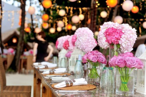 Een lange gedekte trouwtafel buiten in Toscaanse stijl met linnen lopers, terracotta bloempotten, kaarsen en wilde bloemen