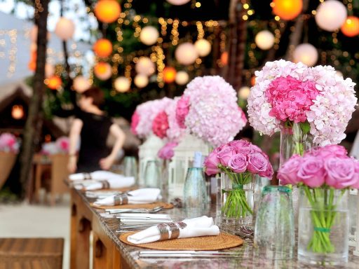 Een lange gedekte trouwtafel buiten in Toscaanse stijl met linnen lopers, terracotta bloempotten, kaarsen en wilde bloemen