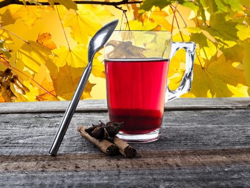 Een dampend kopje kruidenthee op een houten tafel in een herfstse sfeer