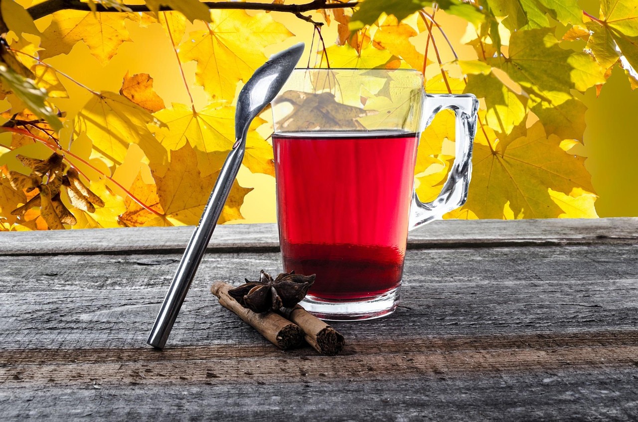 Een dampend kopje kruidenthee op een houten tafel in een herfstse sfeer