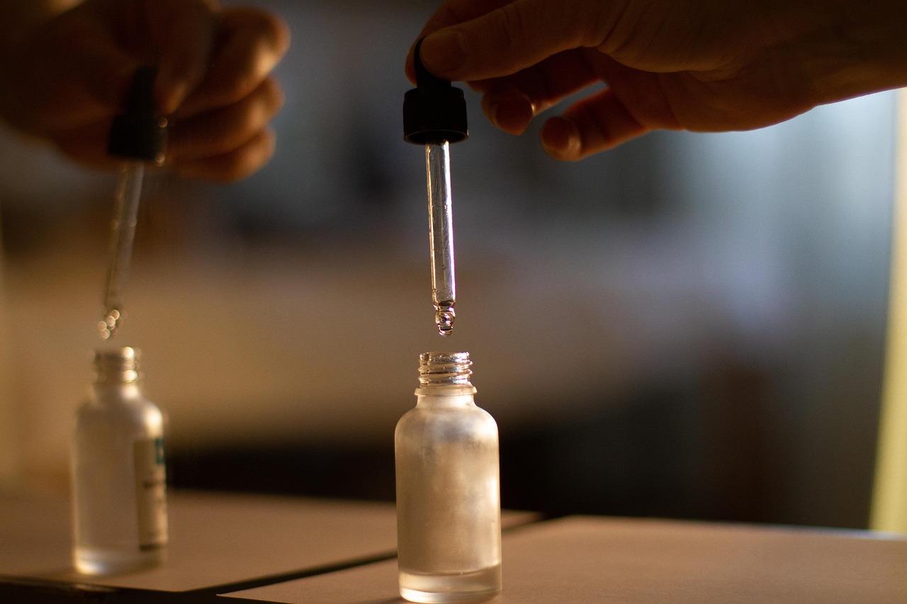 Een flesje nagelolie met pipet naast verzorgde handen met goed onderhouden nagels